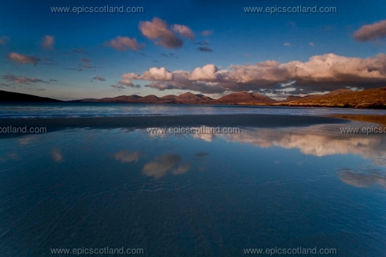 Image: Luskentyre Beach, Isle of Harris, Western Isles, looking across to the North Harris Hills, 
                       late afternoon winter sunshine. Reflections of blue sky and white cloud in 
                       the calm sea, low tide at point of turning.