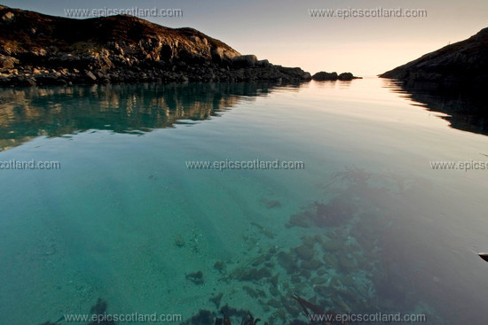 Image: Stretch of calm blue seawater, between 
                       the main Isle of Harris and offshore island, clean shell sand seabed, kelp and other seaweed 
                       visible near the rocky shore.